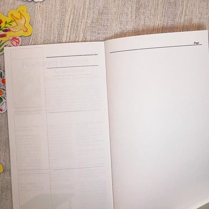 An open planner or notebook showing blank white pages with faint gray layout lines and a page header reading 'Page' on the right side, photographed from above on a light wood surface with small colorful floral props at the left edge.