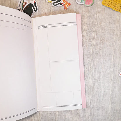 An open planner or notebook with a folded blank white pages, photographed from above on a light wood surface with small decorative stickers around the edges.