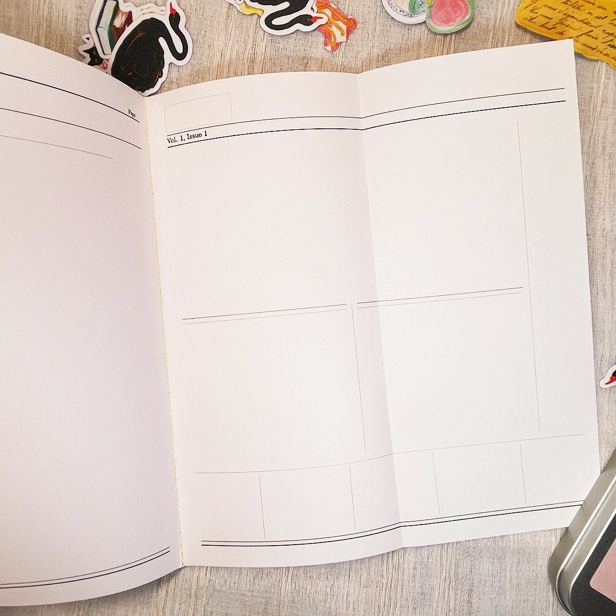 An open planner or notebook with an unfold blank lined pages, photographed from above on a light wood surface with small decorative stickers around the edges.